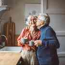 Ehepaar trinkt zuhause glücklich einen Kaffee zusammen.