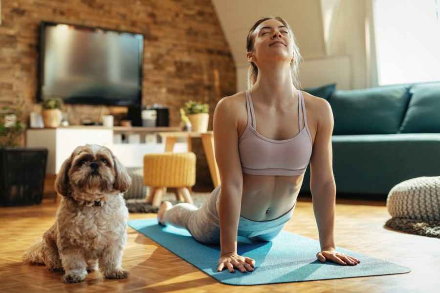 Eine junge Frau macht mit Ihrem Hund gemeinsam Yoga.