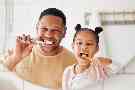 Ein Vater bringt seiner Tochter bei, wie man seine Zähne gründlich putzt.