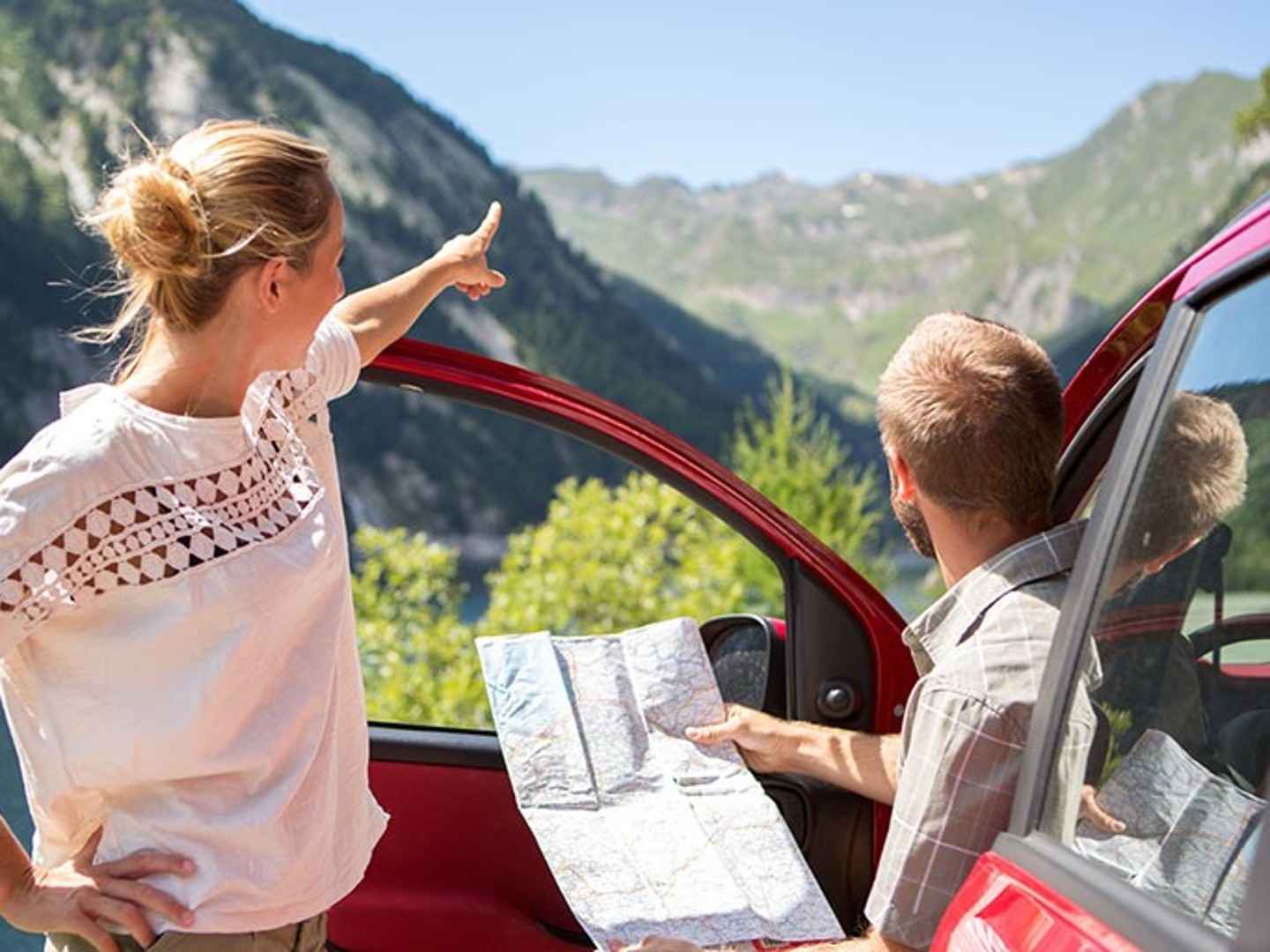Mann sitzt im Auto und fragt eine Frau nach dem Weg