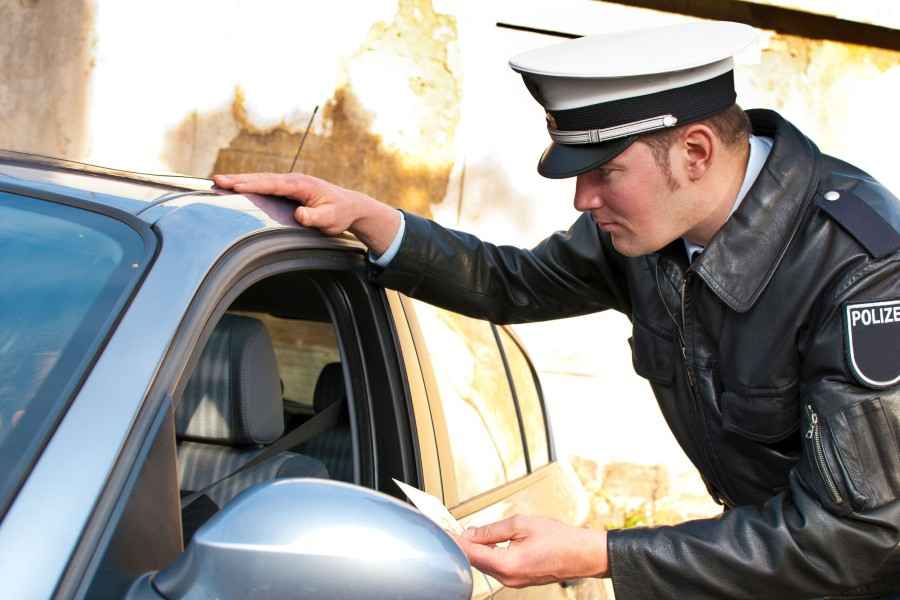 Gothaer Ratgeber Auto Bußgeldkatalog: Polizist kontrolliert einen Autofahrer.