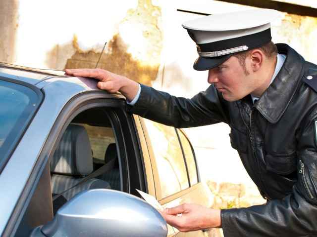 Gothaer Ratgeber Auto Bußgeldkatalog: Polizist kontrolliert einen Autofahrer.