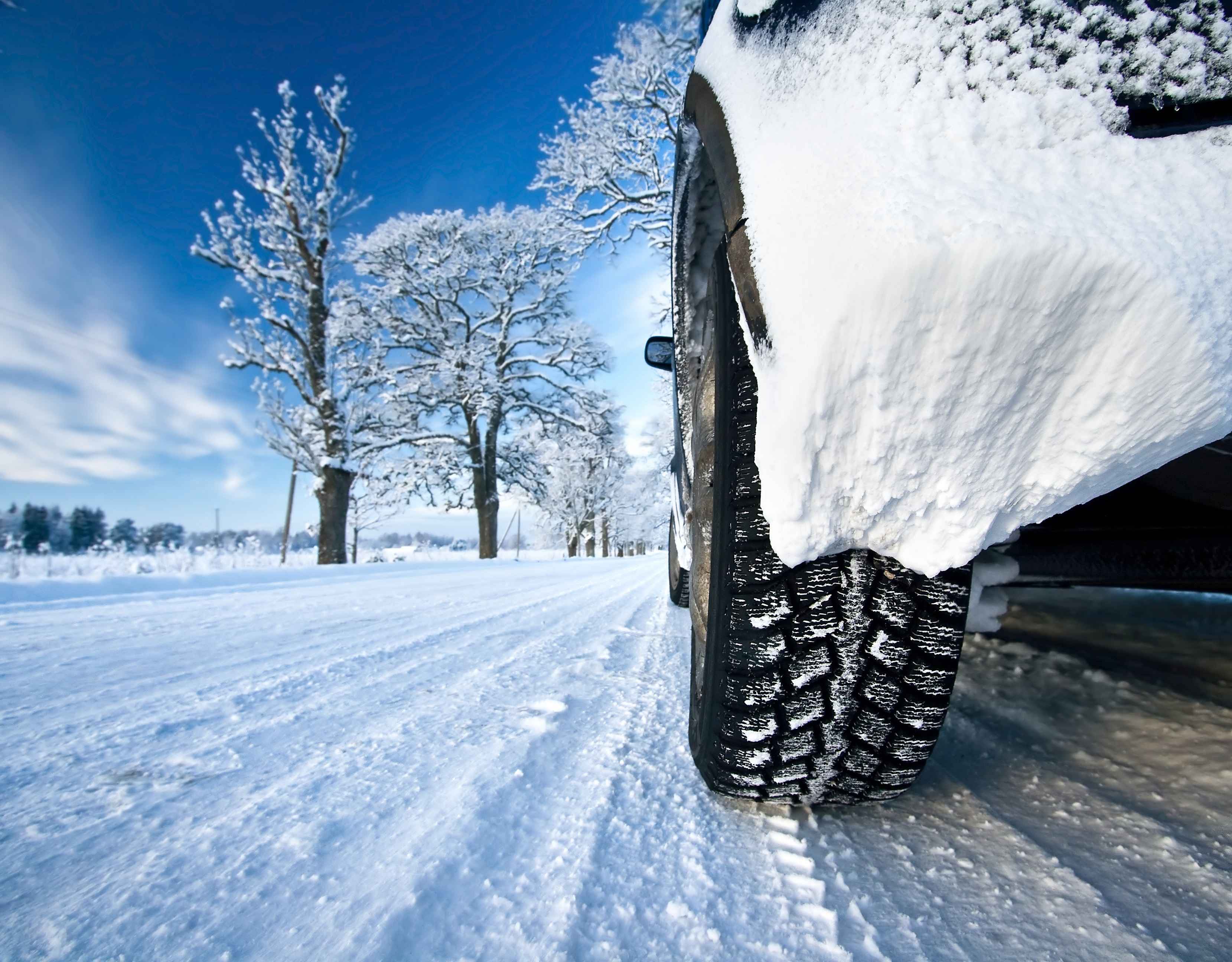 Ein Auto mit Winterreifen fährt über eine schneebedeckte Straße