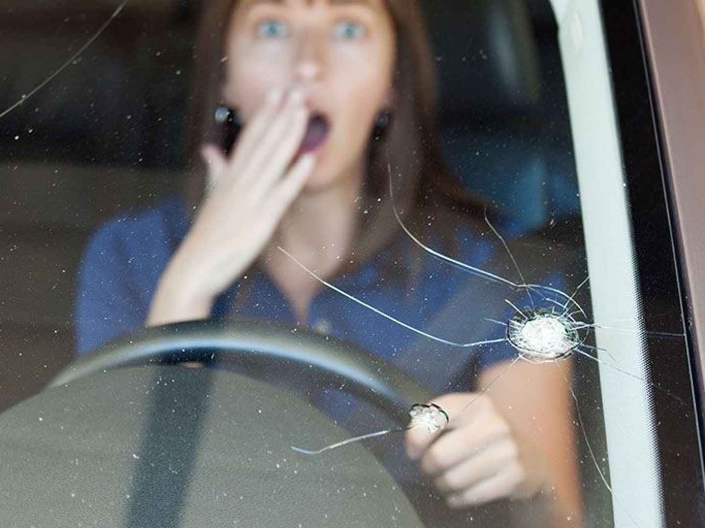 Frau erschrickt über Steinschlag auf der Windschutzscheibe