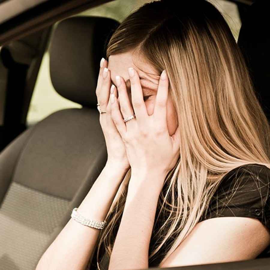 Frau im Auto schlägt die Hände vors Gesicht