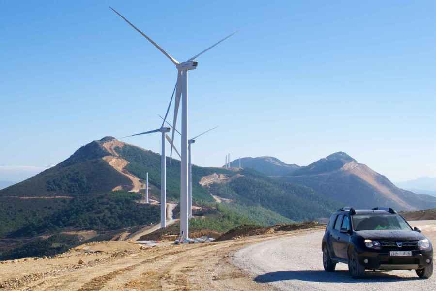 In der Natur stehen Windräder und ein Auto fährt entlang.