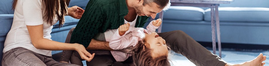 Hausratversicherung: Familie spielt im Wohnzimmer. Hausratversicherung: Familie spielt im Wohnzimmer.