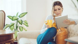 Wohnungsversicherung: Frau in ihrer Wohnung auf dem Sofa Wohnungsversicherung: Frau in ihrer Wohnung auf dem Sofa